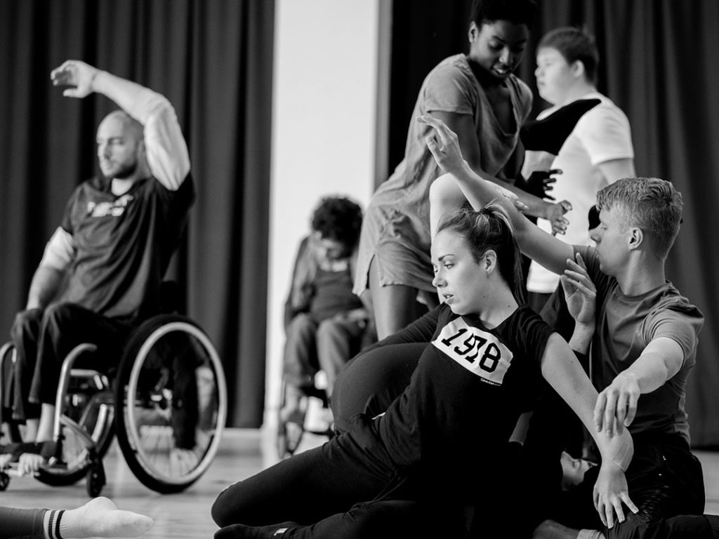 dansers met en zonder rolstoel bewegen met hun armen