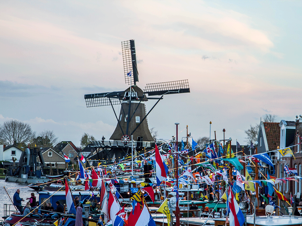 Decoratieve afbeelding van een Fries dorp, versierd met vlaggetjes en een molen