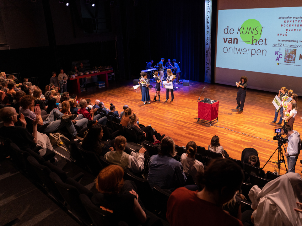 overview van een theaterzaal. Op het podium vindt een prijsuitreiking plaats.